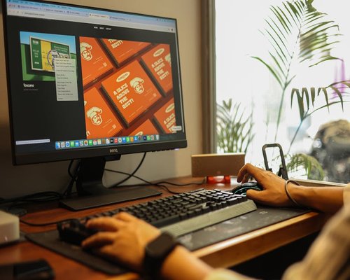 Seorang desainer mengatur jarak pandang monitor di meja kerjanya yang terang